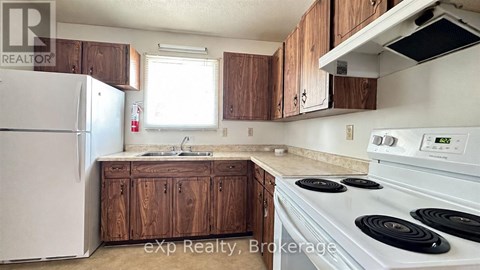 A kitchen with a white stove top oven and a white refrigerator.
