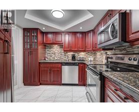 A kitchen with red cabinets and a stone backsplash.