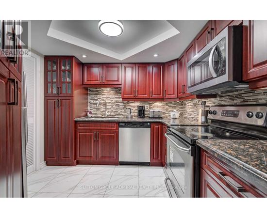 A kitchen with red cabinets and a stone backsplash.