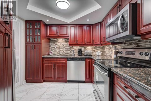 A kitchen with red cabinets and a stone backsplash.