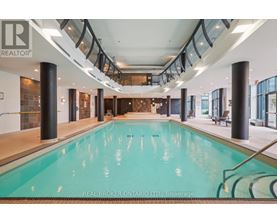 A large indoor swimming pool with a glass ceiling and a Real Broker logo.