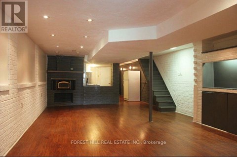 A spacious living room with wood flooring and a staircase.