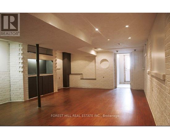 A spacious room with wood flooring and white brick walls.
