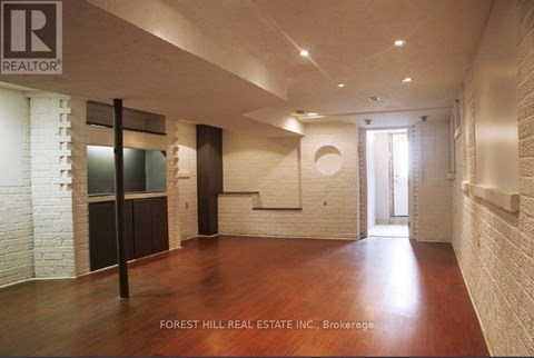A spacious room with wood flooring and white brick walls.
