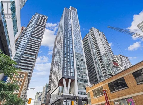 A tall building with the letter V on it stands in front of other buildings.