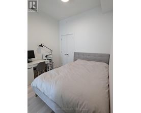 A bedroom with a bed, desk, and chair.