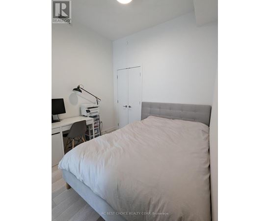 A bedroom with a bed, desk, and chair.
