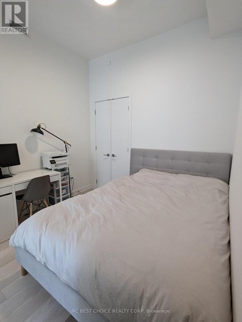 A bedroom with a bed, desk, and chair.