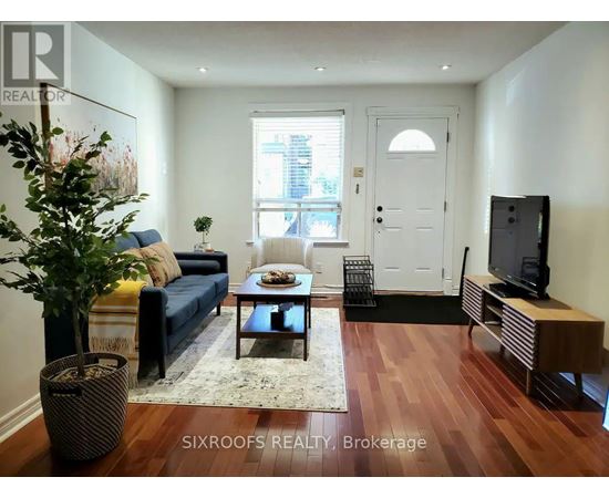 A living room with a blue couch and a wooden floor.