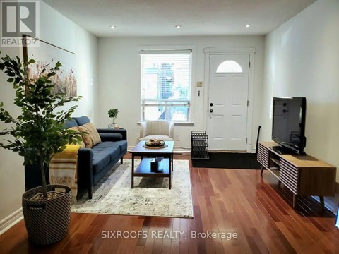 A living room with a blue couch and a wooden floor.