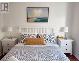A bedroom with a bed, two nightstands, and a painting on the wall.