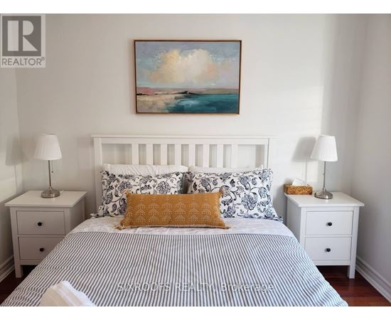 A bedroom with a bed, two nightstands, and a painting on the wall.