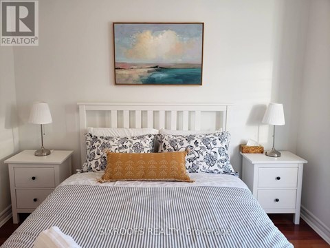 A bedroom with a bed, two nightstands, and a painting on the wall.
