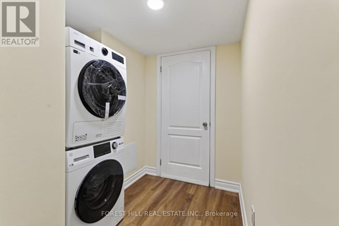 A Forest Hill Real Estate Inc. brokerage logo is displayed on a wall above a washer and dryer in a small laundry room.