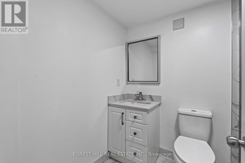 A bathroom with a toilet, sink and mirror.