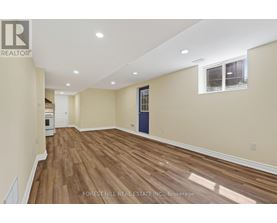A room with wooden flooring and a window with a view of trees.