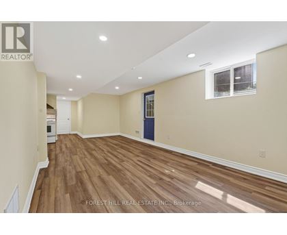 A room with wooden flooring and a window with a view of trees.