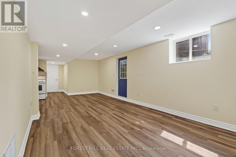 A room with wooden flooring and a window with a view of trees.