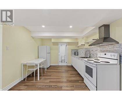 A kitchen with a table and chairs in the foreground and a stove top oven in the background.