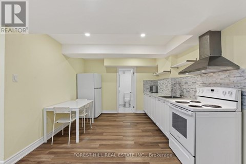 A kitchen with a table and chairs in the foreground and a stove top oven in the background.