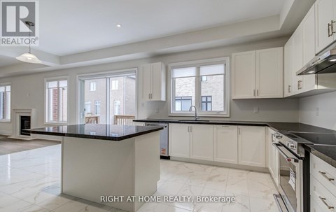 A spacious kitchen with marble countertops and white cabinets.