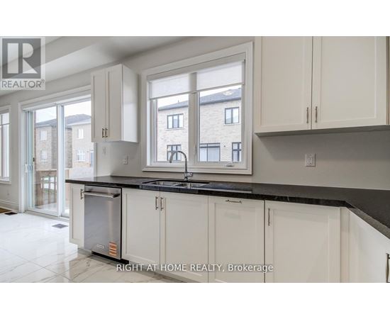A kitchen with white cabinets and a black countertop.