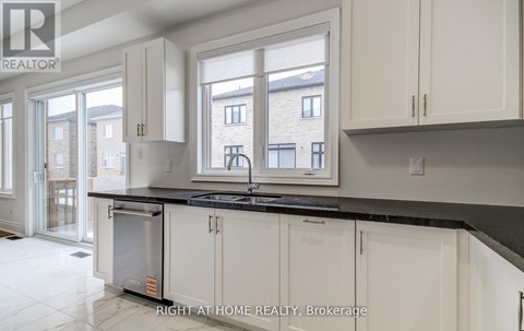 A kitchen with white cabinets and a black countertop.