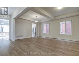 A spacious room with wooden flooring and two windows.