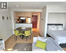 A bedroom with a bed, a table and chairs, and a nightstand.