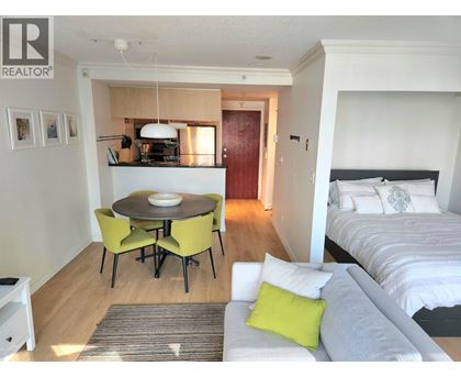 A bedroom with a bed, a table and chairs, and a nightstand.