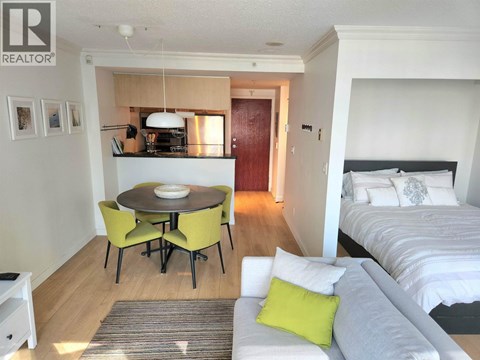 A bedroom with a bed, a table and chairs, and a nightstand.