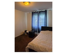 A bedroom with a bed, a basket, and a speaker.