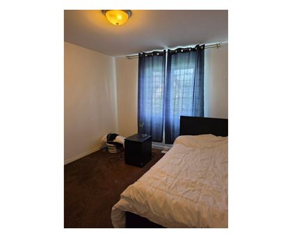 A bedroom with a bed, a basket, and a speaker.