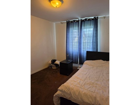A bedroom with a bed, a basket, and a speaker.
