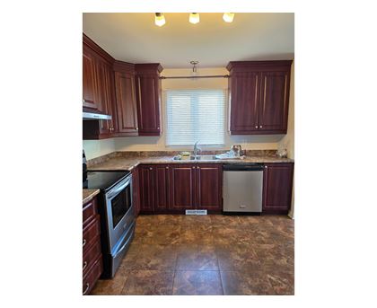 A kitchen with brown cabinets and a tiled floor.
