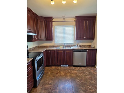 A kitchen with brown cabinets and a tiled floor.