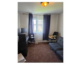 A living room with a couch, chair, and television.