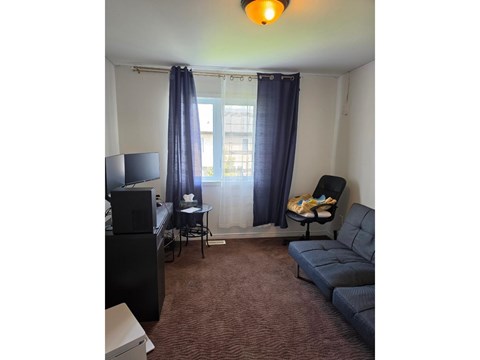A living room with a couch, chair, and television.