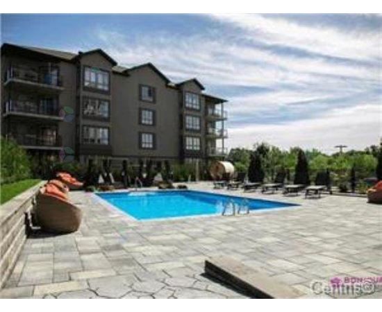 A large apartment complex with a pool in the foreground.