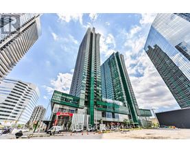 A modern glass building stands tall among other skyscrapers on a sunny day.