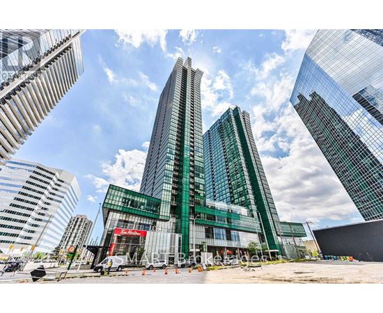 A modern glass building stands tall among other skyscrapers on a sunny day.