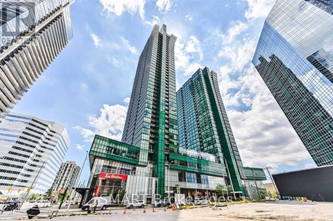 A modern glass building stands tall among other skyscrapers on a sunny day.