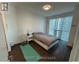 A bedroom with a bed, nightstand, and window.