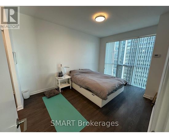 A bedroom with a bed, nightstand, and window.