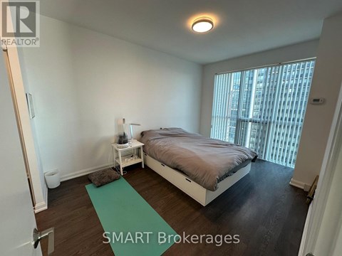 A bedroom with a bed, nightstand, and window.