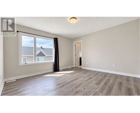 A spacious room with a large window and wooden flooring.