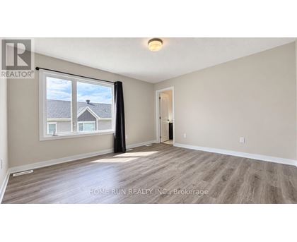 A spacious room with a large window and wooden flooring.
