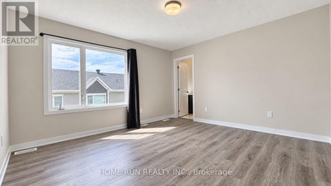 A spacious room with a large window and wooden flooring.