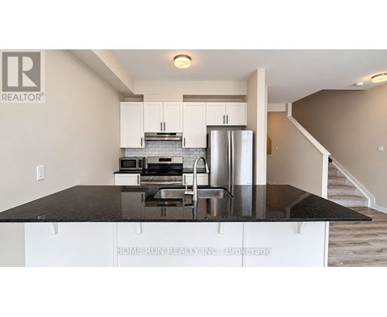 A kitchen with white cabinets and a black countertop.