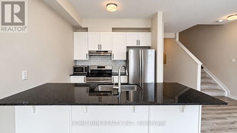 A kitchen with white cabinets and a black countertop.